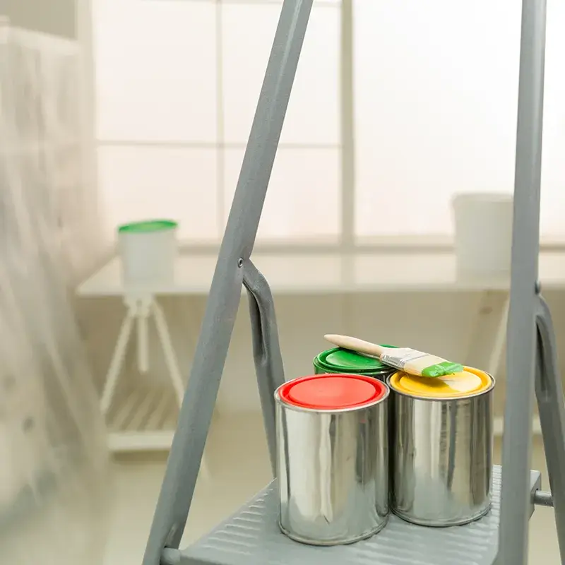 a paintbrush on paint cans on a ladder